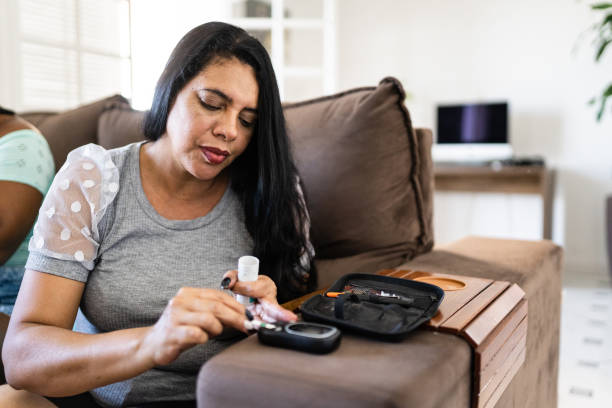 mujer que controla el nivel de azúcar en la sangre en casa - diabetes fotografías e imágenes de stock