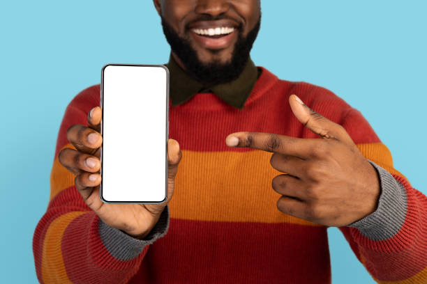 istock Mobile Offer. Smiling Black Man Pointing At Black Smartphone In Hand 1384902894