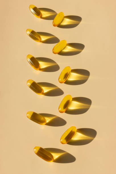 capsules d’oméga-3, oméga-6, oméga-9 dans une lumière dure avec des ombres de pilules.  médecine préventive qui aide à construire et à maintenir un corps sain. santé. prendre des suppléments beige, fond vertical - capsule fish oil fish pill photos et images de collection