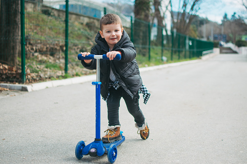 Little boy riding a push scooter