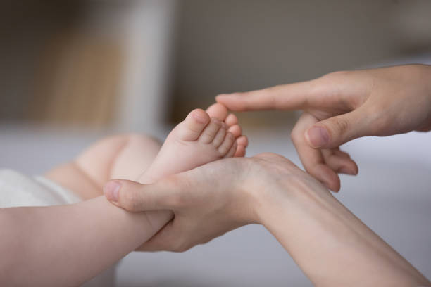 Hands of mom touching little baby tiny feet, caressing kid