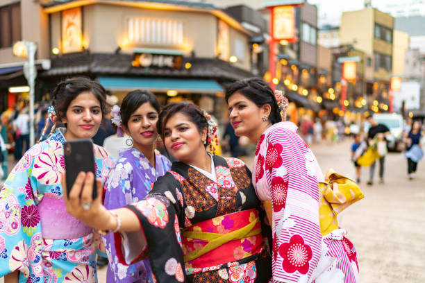 Female friends experiencing wearing Kimono and taking selfies with a smart phone while sightseeing in Japan