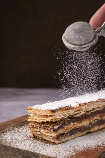 Chocolate millefeuille with sugar falling on it