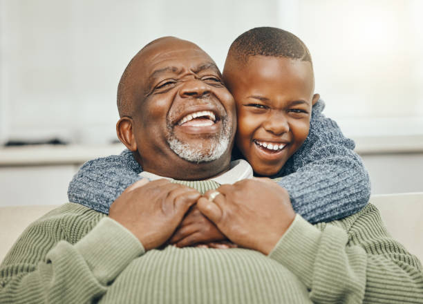 снимок дедушки, скрепляющегося со своим маленьким внуком на диване дома - grandfather стоковые фото и изображения