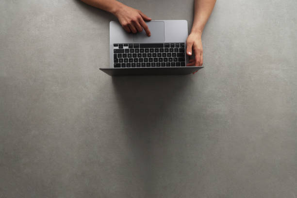 istock Woman using laptop on gray background with copy space 1384936033