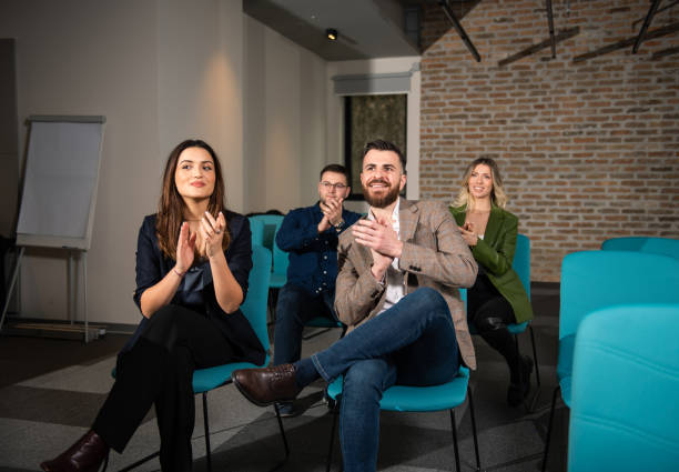 istock Smiling audience applauding at a business seminar 1384936714