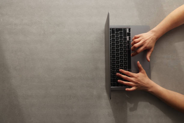 istock Woman using laptop on gray background with copy space 1384936982