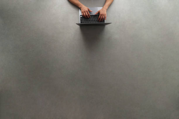 istock Woman using laptop on gray background with copy space 1384939247