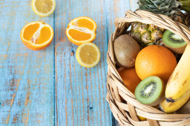 istock Wicker basket with fresh tropical fruit isolated on a wooden table 1384939262