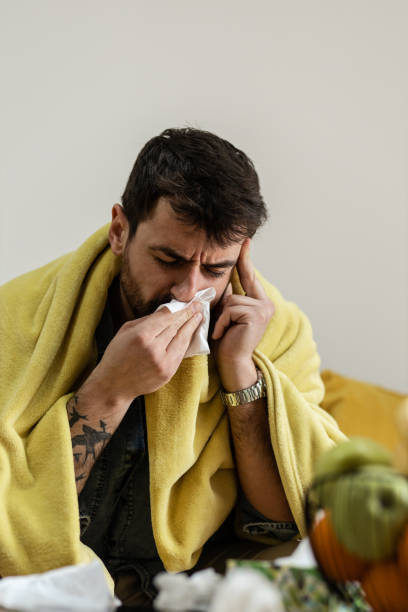 istock Young man wiping nose with a tissue 1384950134