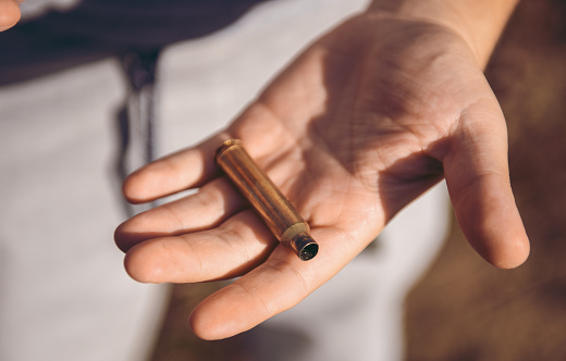 Bullet casing in hand. During a walk in the woods a man found a bullet casing. Hunting.