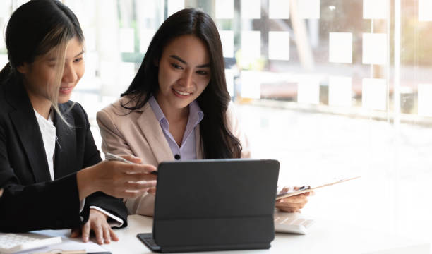 istock Two beautiful young asian businesswoman working together using digital tablet at office. 1384968586