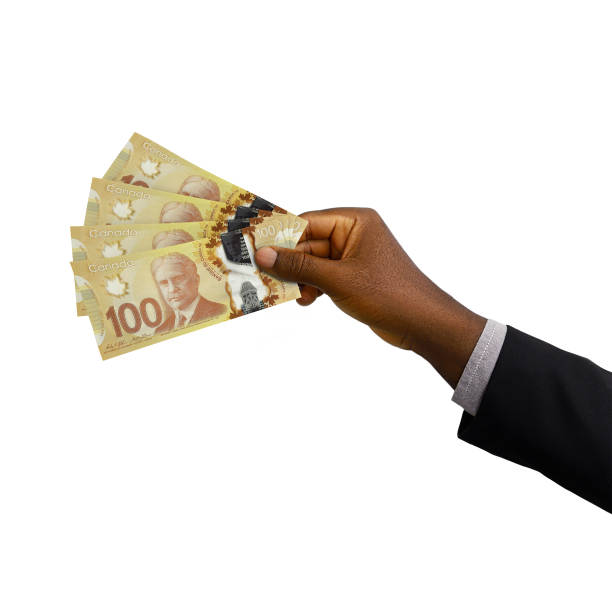 istock Black hand with suit holding 3D rendered Canadian dollar notes isolated on white background 1384978417