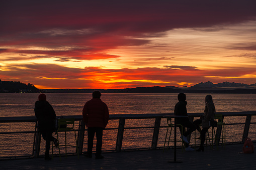 Seattle, USA - Feb 5, 2022: People enjoying the new pier 62 during a vivid sunset over Elliott bay.