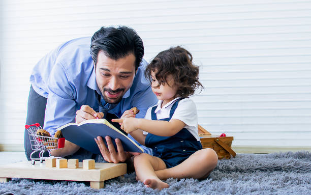 istock Handsome single Caucasian father, little cute adorable daughter playing toy, writing, doing homework together with happiness in living room at cozy home after finish working. Kid, Education Concept. 1384992437