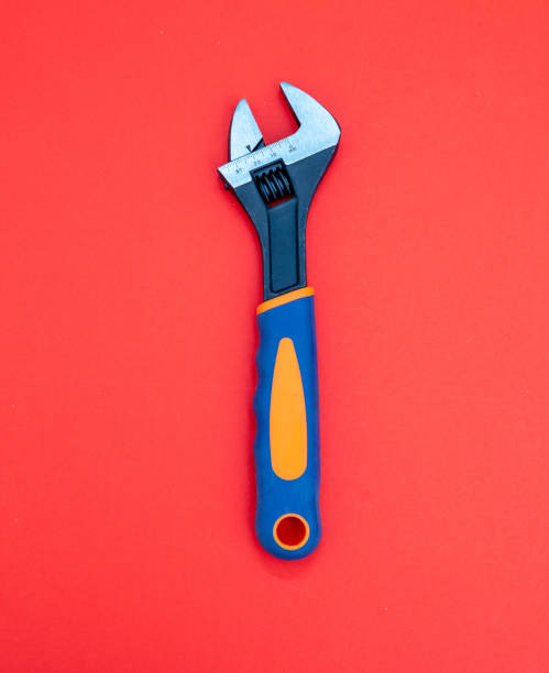 istock Adjustable wrench with graduated scale, orange, blue color rubber handle on red background. Vertical 1384994550