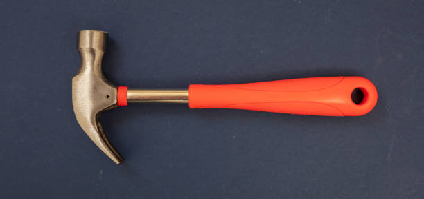 istock Hammer with steel head and orange color rubber handle on blue background. 1384994556