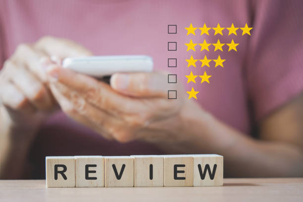 review text on wooden block with blurred senior woman holding smartphone , check box and rating star for customer experience, satisfaction survey, e-commerce performance concept texto de revisión en bloque de madera con mujer mayor borrosa sosteniendo teléfono inteligente, casilla de verificación y estrella de calificación para la experiencia del cliente, encuesta de satisfacción, concepto de rendimiento de comercio electrón