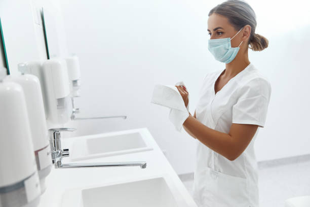 Hygiene, health care.  Close up of female doctor or nurse drying hands with paper tissue at hospital stock photo