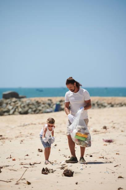 istock Father and Daughter Cleaning Beach Together 1385009551