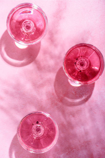 istock Pink champagne in glasses on marble table with palm shadow 1385012269