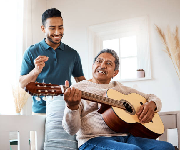 Shot of a young man listening to his father play the guitar at home Nothing sweeter than the sound a guitar makes father and son guitar stock pictures, royalty-free photos & images