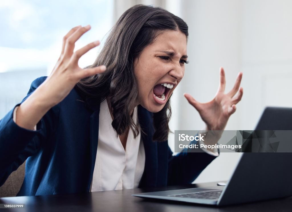 Shot of a young businesswoman yelling while using a laptop in an office at work A goal without a plan is just a wish Anger Stock Photo