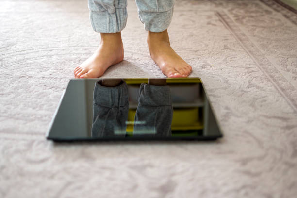 una ragazza a piedi nudi con il peso - weight scale dieting weight loss foto e immagini stock