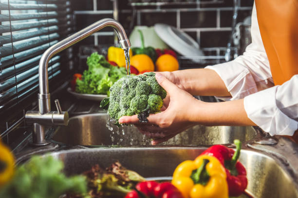 hand of maid washing tomato fresh vegetables preparation healthy food in kitchen - legumes imagens e fotografias de stock