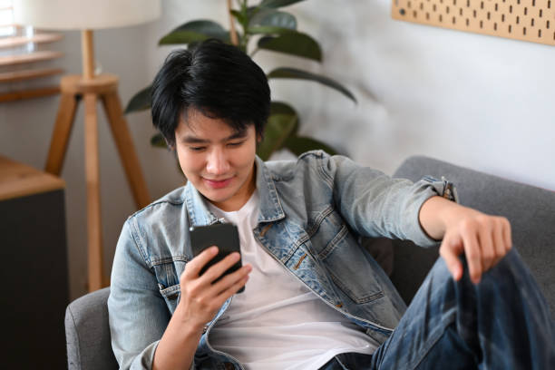 istock Happy casual man sitting on couch and using smart phone for checking social media. 1385042069