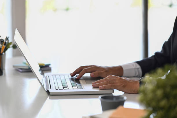 istock Cropped shot businessman hand typing on laptop computer while working at office desk. 1385042114