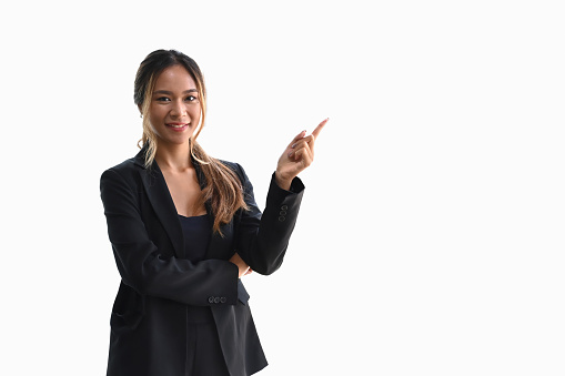 Portrait of smiling businesswoman in suit pointing finger at copy space isolated on white background.