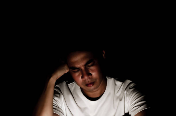 istock Asian miserable depressed man sitting alone in dark background. 1385046824