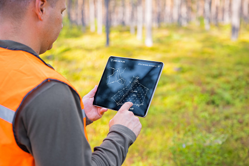 Forester usando una tableta en el bosque y mirando el mapa topológico o el plan de tierras photo