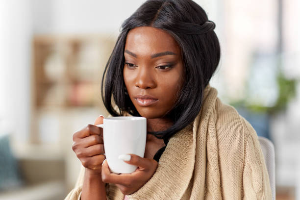 sick african amercian woman drinking tea at home