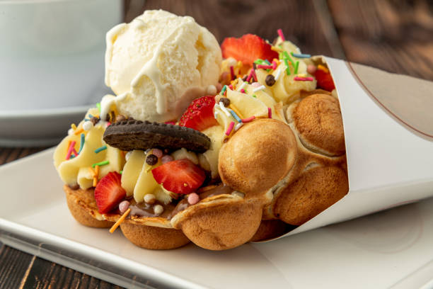 Hong kong or bubble waffle with ice cream, fruits, chocolate sauce and colorful candy stock photo