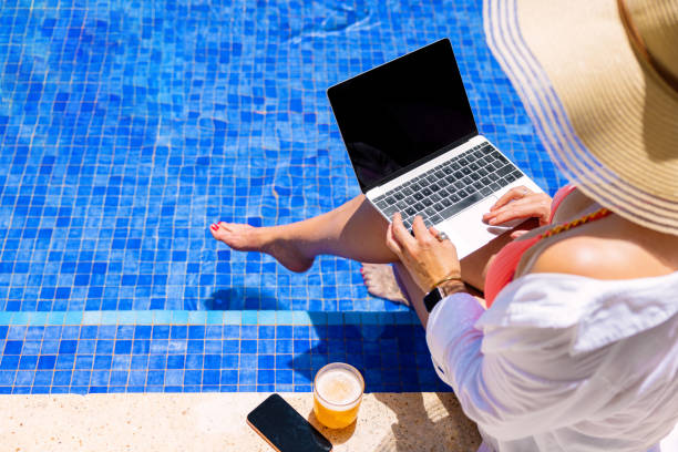 istock Woman using laptop by the pool 1385053546