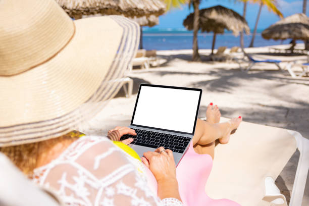 istock Woman using laptop on tropical beach 1385053560