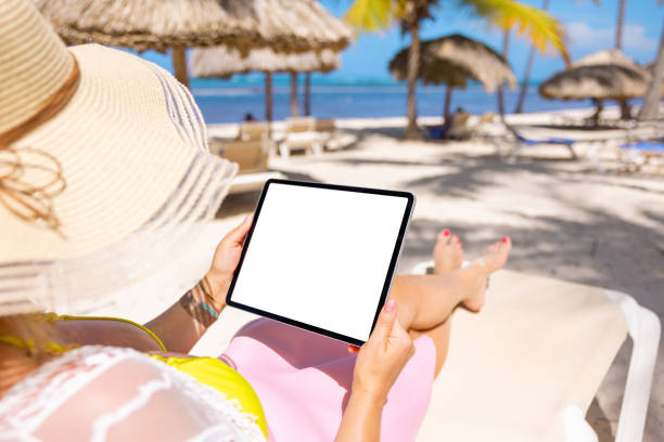 istock Woman holding tablet in hands while relaxing on beach 1385053569