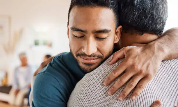 Photo of Shot of a father and son hugging at home