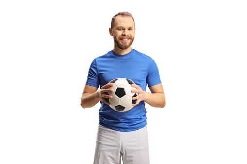 Football player in a blue jersey and white shorts holding a ball and smiling isolated on white background