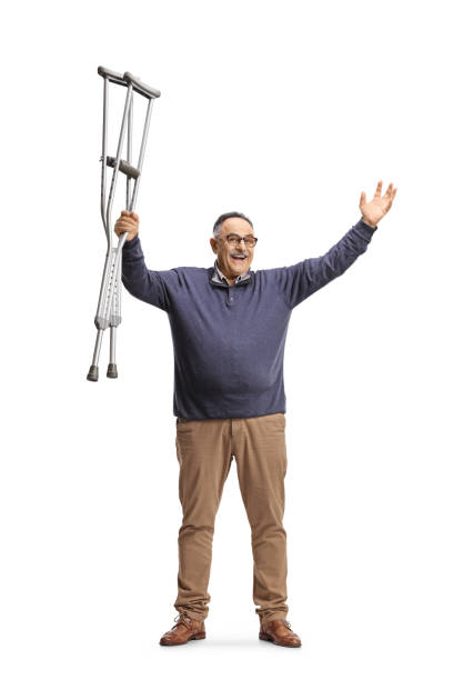 istock Happy mature man raising crutches and gesturing happiness 1385059613
