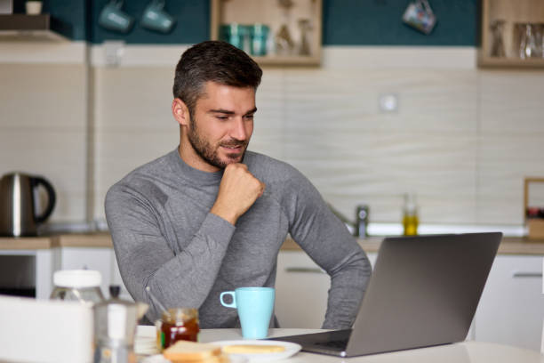 istock Young man doing a video call on his laptop during breakfast 1385062002