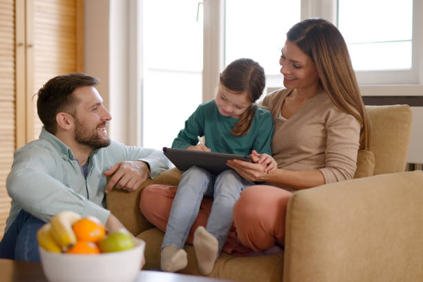 istock Happy parents and their daughter using digital tablet at home 1385062011