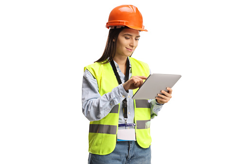 Young female engineer with a safety vest and helmet using a tablet isolated on white background