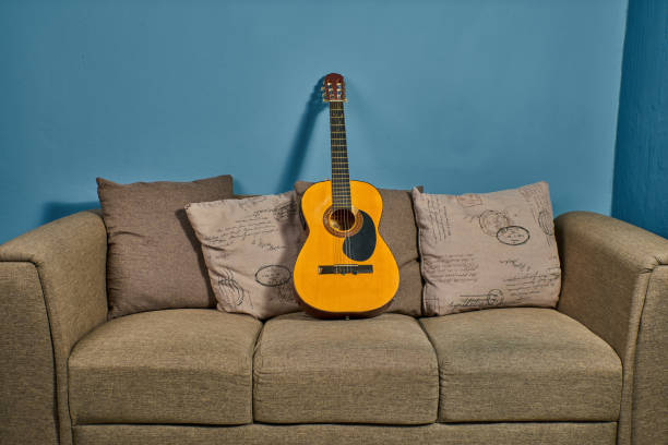 Acoustic Guitar on an armchair ready to start playing stock photo
