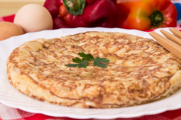 Slices of spanish omelette, a beloved traditional dish featuring eggs, potatoes, and onions, are beautifully arranged on a white plate, inviting enjoyment and satisfaction