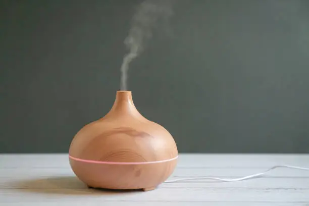 Aroma essential oil diffuser on table. Grey background, copy space.