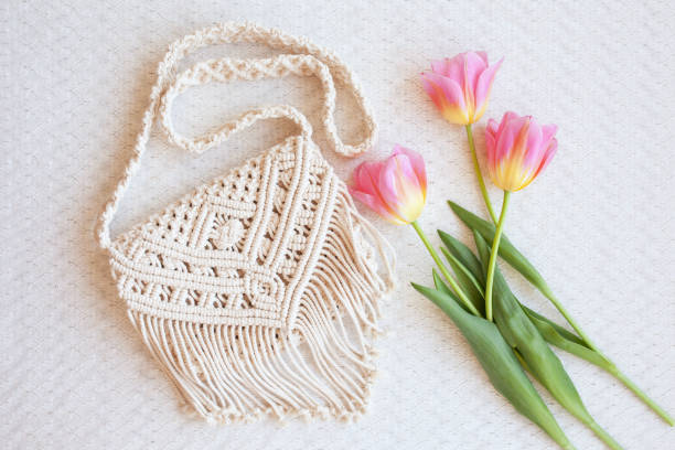 istock Handmade macrame bag with flowers on the light table. ECO friendly natural macrame cotton cross-body bag. Hobby knitting handmade macrame. Modern summer concept. 1385071204