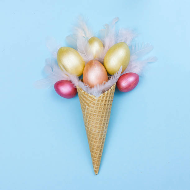 istock Easter eggs with feathers in the waffle cone on blue background. 1385071622